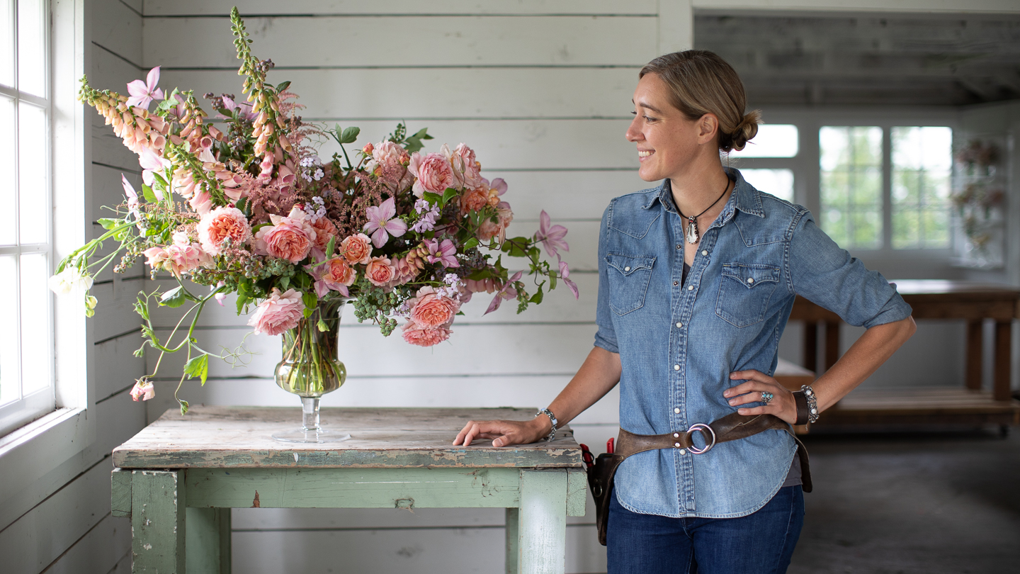 Erin Benzakein and an arrangement she created with blooms in shades of pink and peach